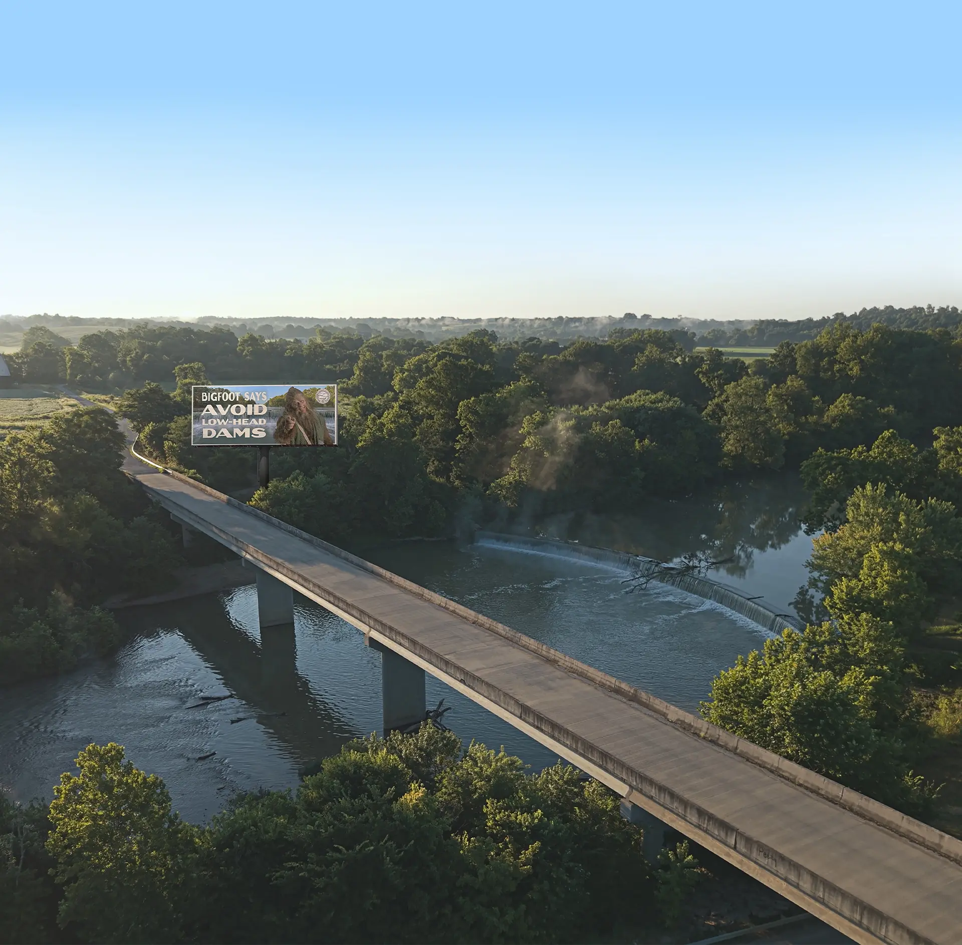 Overhead view of a river and bridge with a Bigfoot dam safety billboard